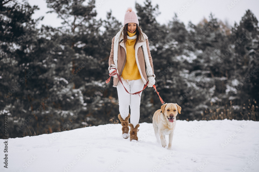 Young woman walking with her dog in a winter park