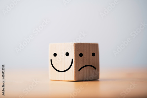 Smile face in bright side and sad face in dark side on wooden block cube for positive mindset selection concept. photo