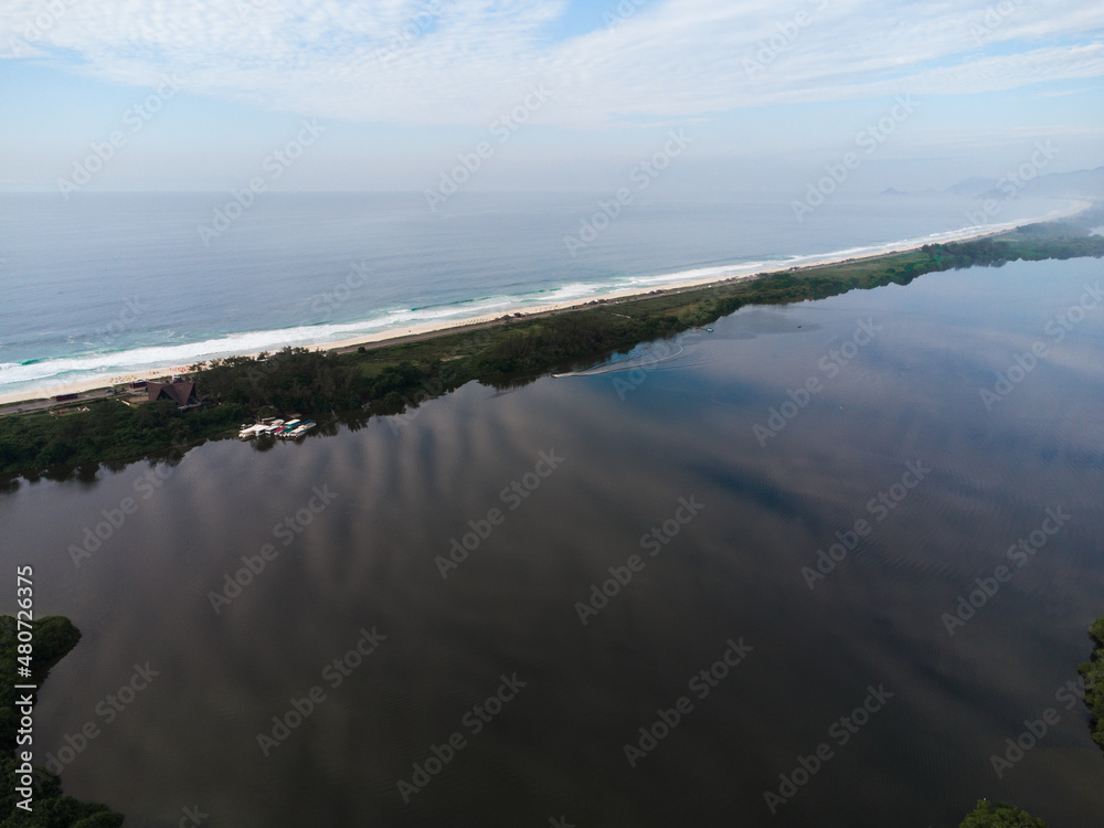Aerial view of Reserva beach and Marapendi lagoon. In the background, the hills of Recreio dos Bandeirantes, in Rio de Janeiro, Brazil. Dawn. Sunny day with some clouds. Drone photo