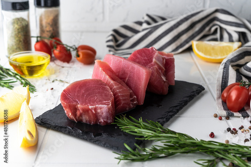 Fresh tuna fillet steaks with spices, vegetables and herbs on a plate. Preparing tuna for baking. High quality photo