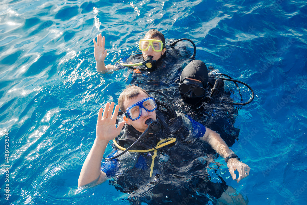 Team of divers man and woman with scuba gear are preparing to dive underwater in red sea, top view