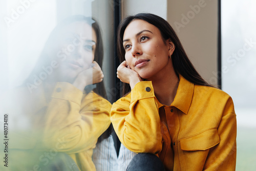 Bilde på lerret Pensive young woman staring out of a window