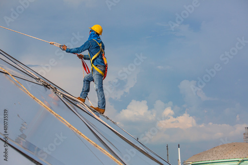 Male workers rope access height safety connecting with a knot safety harness, to ascending, construction site oil tank dome.