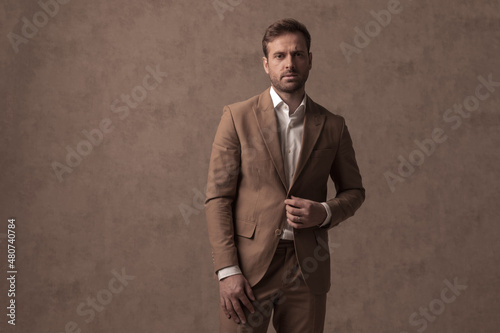 young handsome businessman arranging his jacket and posing