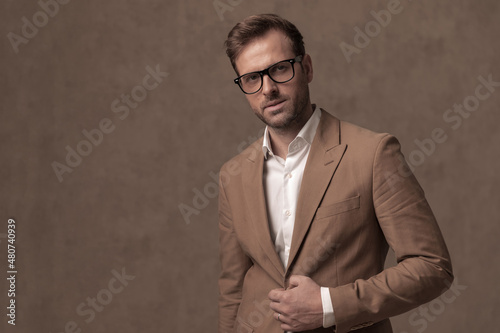 young handsome businessman closing his jacket, wearing eyeglasses