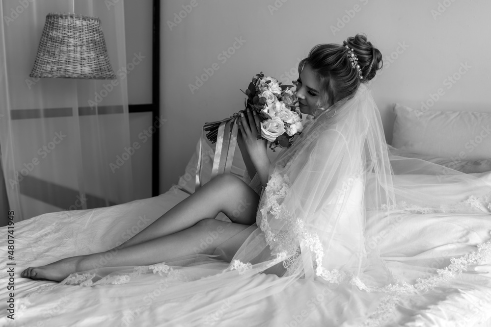 The bride on the bed holds a wedding bouquet. Bride morning. Beautiful bouquet of roses. The bride on the bed holds a wedding bouquet. Bride morning. Beautiful bouquet of roses.