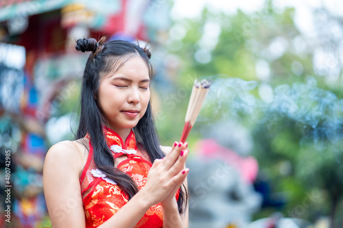Fotografie Asian woman in chinese dress traditional cheongsam holding incense pay homage to Chinese god at shrine