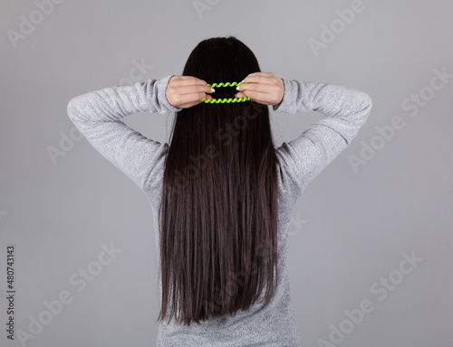 Young woman tie hair. Gray background.