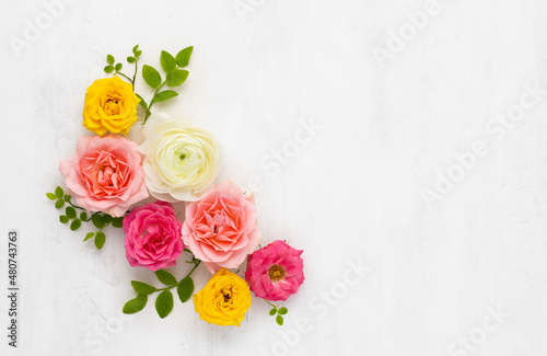 Fototapeta Naklejka Na Ścianę i Meble -  Roses Arrangement. Composition of colorful Roses Flowers and green leaves on light background. Top view