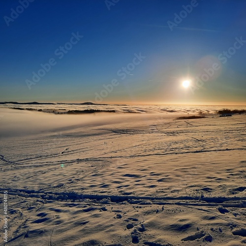 sunset in the snow on top of winter mountain, winter landscape, sunset  background, footprints in the snow,  frame, on top of winter mountain Wasserkuppe in Rhoen Rhön Hesse Germany photo