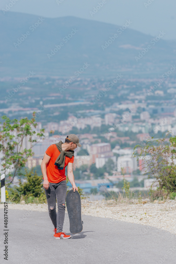 Tall athlete riding his longboard fast and steady downhill while wearing red t-shirt and black jeans. Tall athlete riding his longboard fast and steady downhill while wearing red t-shirt and black jeans.