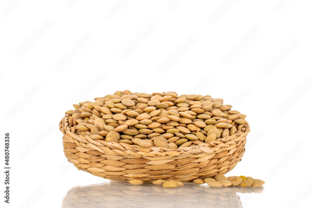 Raw organic green lentils in a straw plate, macro, isolated on white.