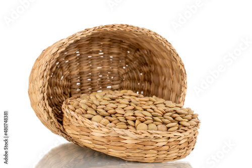 Raw organic green lentils in a straw basket, macro, isolated on white.