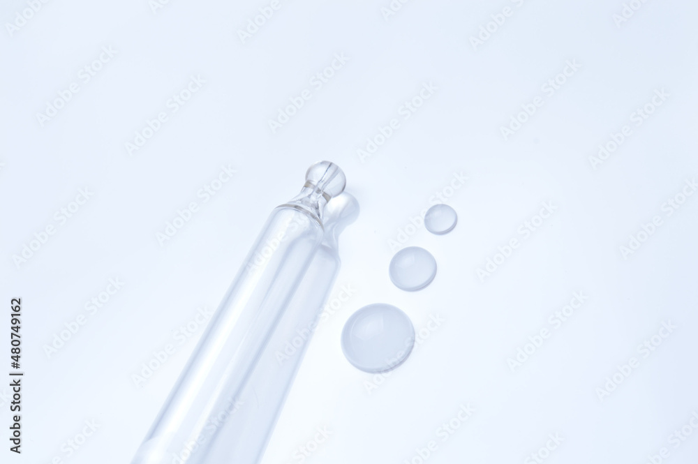 Naklejka premium glass transparent jar and a cosmetic pipette with liquid droplets on a white background.