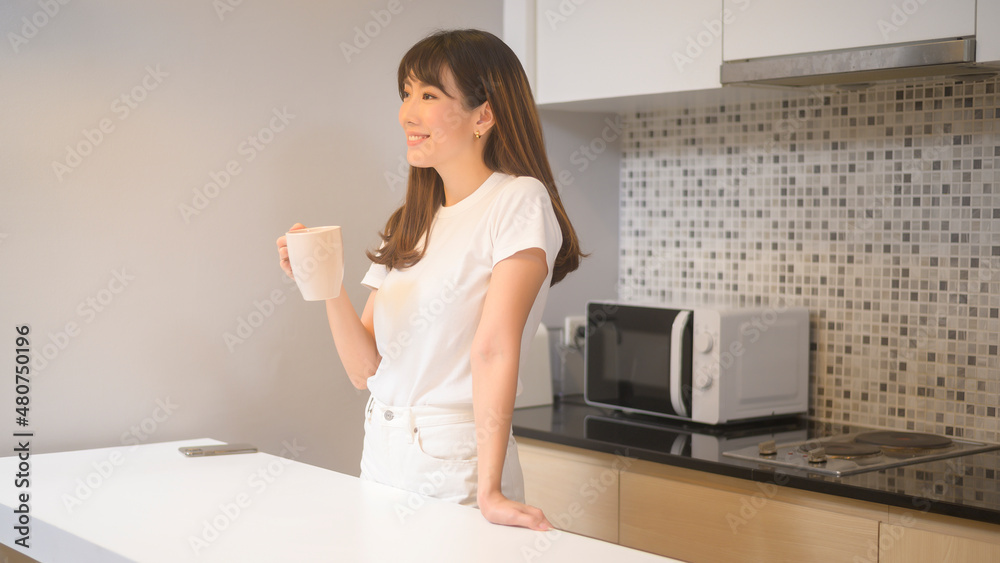 Portrait of young beautiful woman drinking glass of water in kitchen