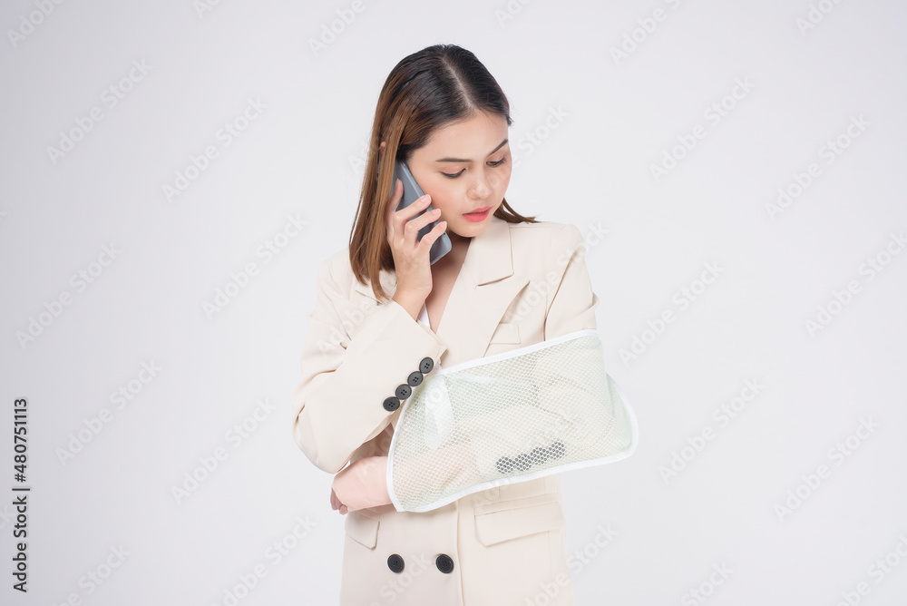 Portrait of young woman with an injured arm in a sling over white background in studio.. Portrait of young woman with an injured arm in a sling over white background in studio..