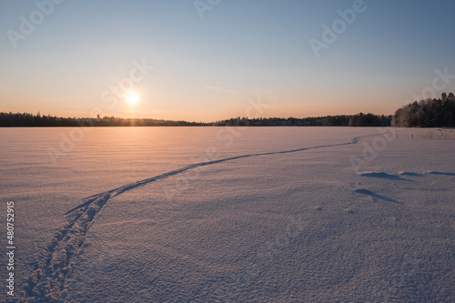 Frozen lake with cross country ski tracks at sunset