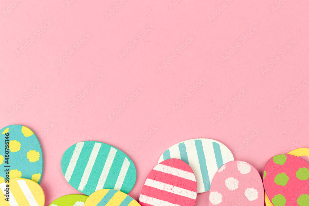 Colorful easter eggs bottom border on a bright pink background. Flat lay celebration greeting design, border concept, copy space and top view photo