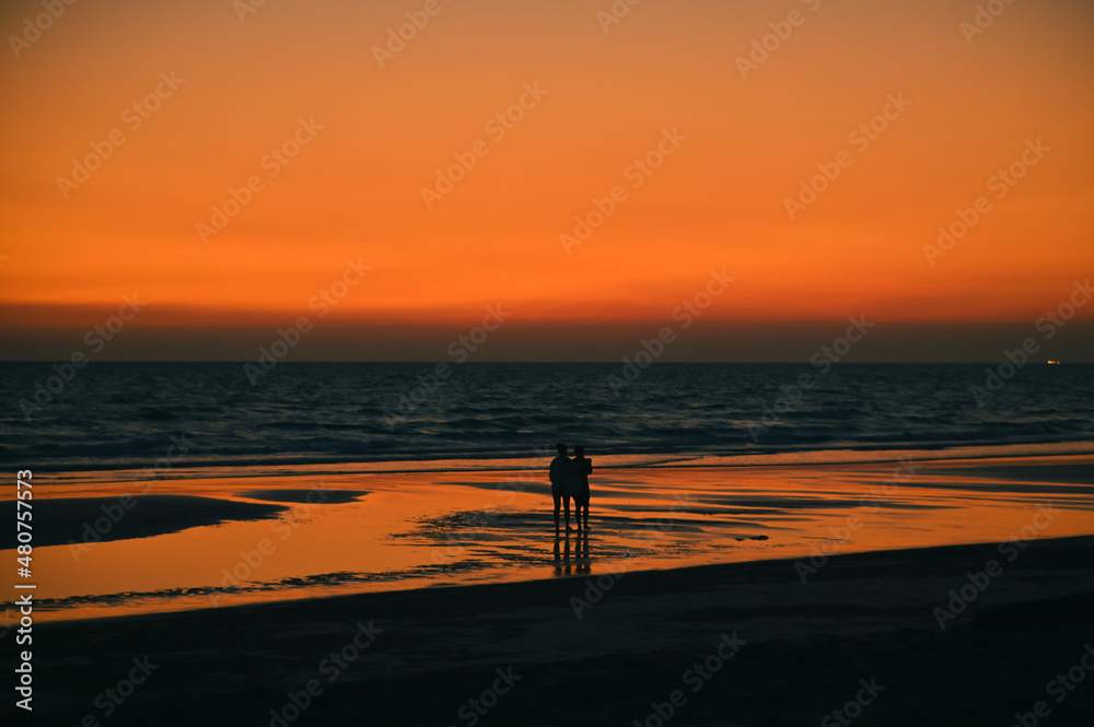 Summer sunset view on the beach. Beautiful blazing sunset landscape and orange sky above it with sun reflection on waves.