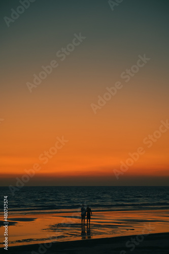 Summer sunset view on the beach. Beautiful blazing sunset landscape and orange sky above it with sun reflection on waves.