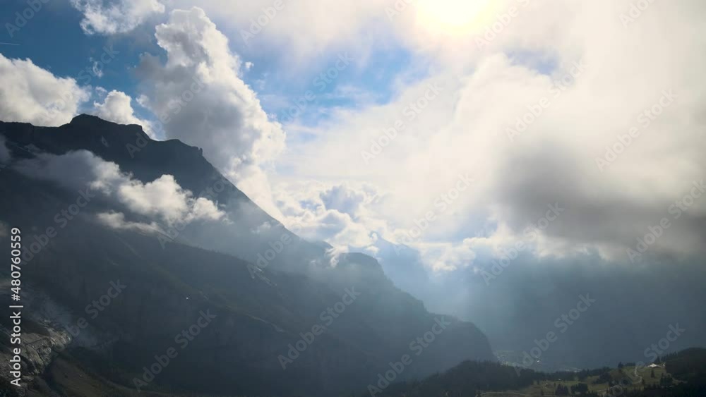 Aerial drone shot of the side of a rocky mountain on a sunny day. Low hanging clouds over a valley between the mountains in the swiss alps. Drone flying thorugh thr clouds. Aerial drone shot of the side of a rocky mountain on a sunny day. Low hanging clouds over a valley between the mountains in the swiss alps. Drone flying thorugh thr clouds.