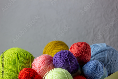 Women's hobby knitting.Yarn of bright colors on a gray background. Place for your text.