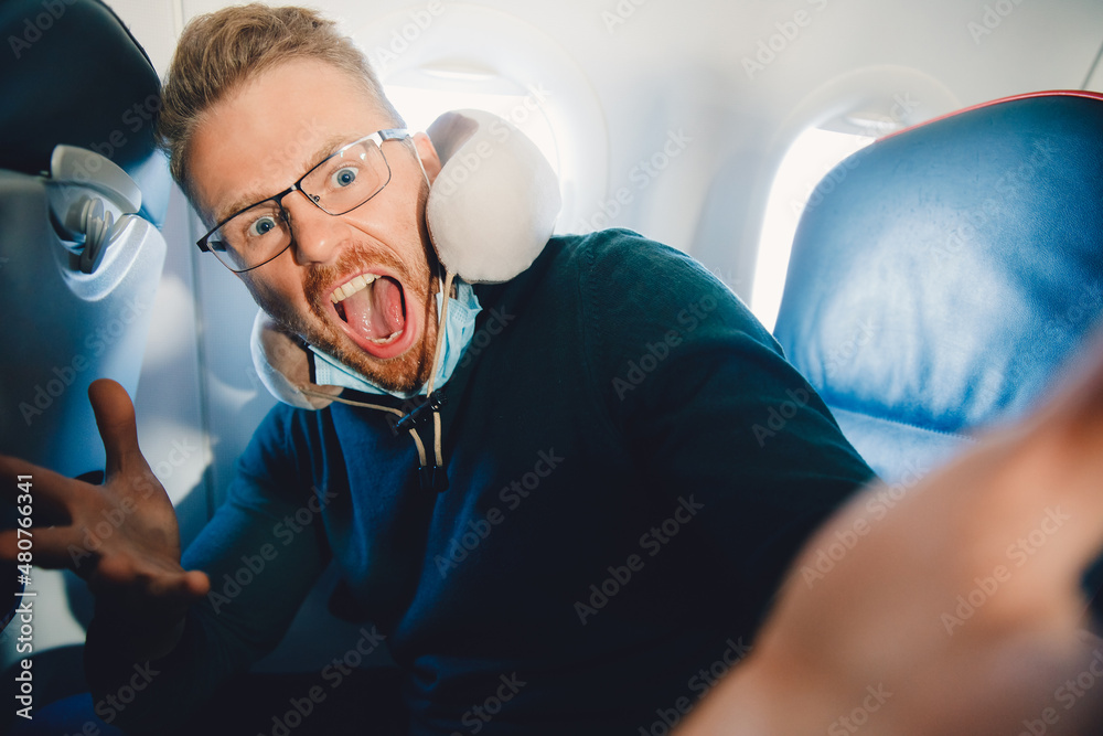Obraz premium Concept of aerophobia, male tourist is afraid of flying on airplane