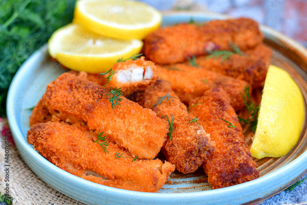 Close up of   Crispy breaded  deep fried fish fingers with breadcrumbs served  with remoulade sauce and  lemon Cod Fish Nuggets on rustic wood table background