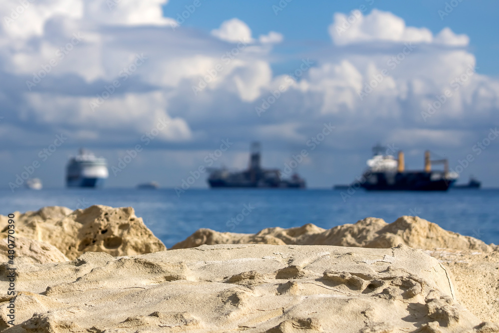 Big white rock and blurred sea with ships on the horizon and cloudy sky Big white rock and blurred sea with ships on the horizon and cloudy sky
