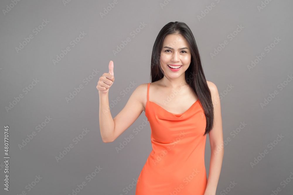 Fashion portrait of beautiful woman wearing orange dress isolated over gray background studio Fashion portrait of beautiful woman wearing orange dress isolated over gray background studio