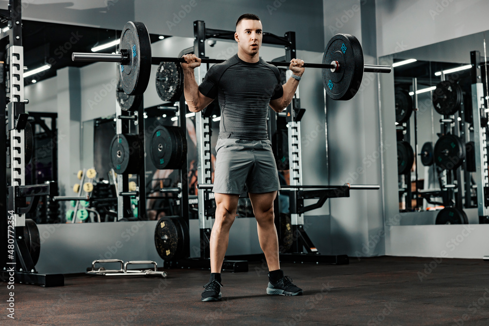 A muscular bodybuilder doing strength exercises with weights in a gym. A muscular bodybuilder doing strength exercises with weights in a gym.