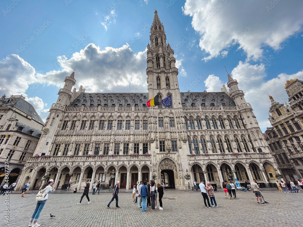 Gothic town hall building in Brussels, capital of Brussels and Europe, at the Grand Place with tourists and blue sky with white clouds