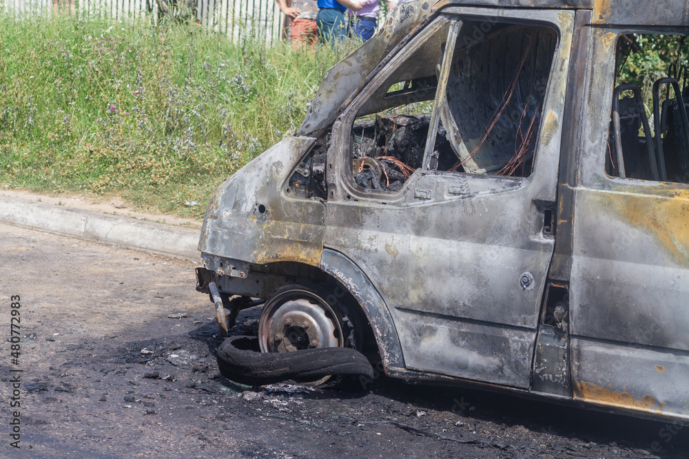 The car after the fire is covered with black soot on the city street