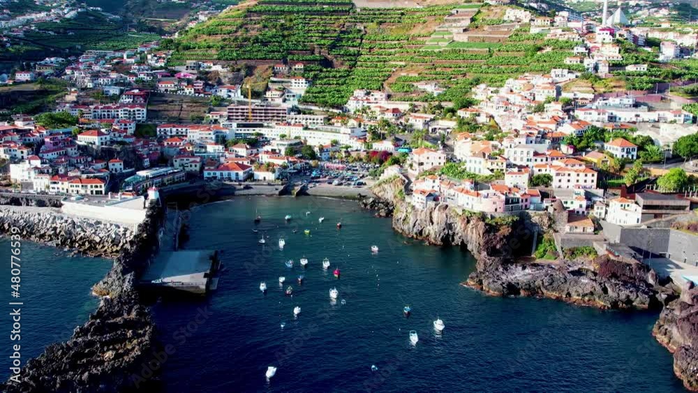 Aerial 4K footage of drone flight over Camara de Lobos fisherman village in Madeira Island with a bay with many small boats