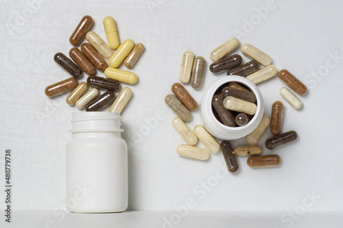 Capsules with dietary supplements or vitamins in white plastic jars photo