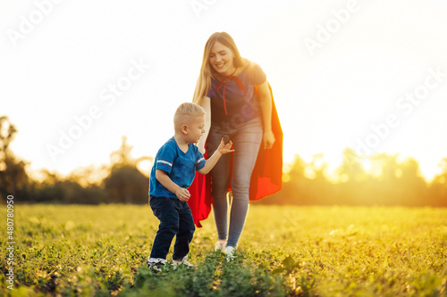 mom and son plant a tree in the park  mom and son in superhero costumes  Side view of a happy family plant a tree