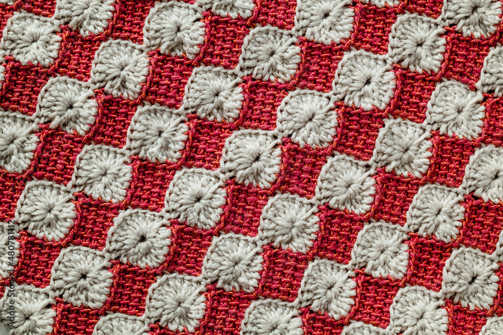 White and red crocheted floral pattern. Knitted texture.
