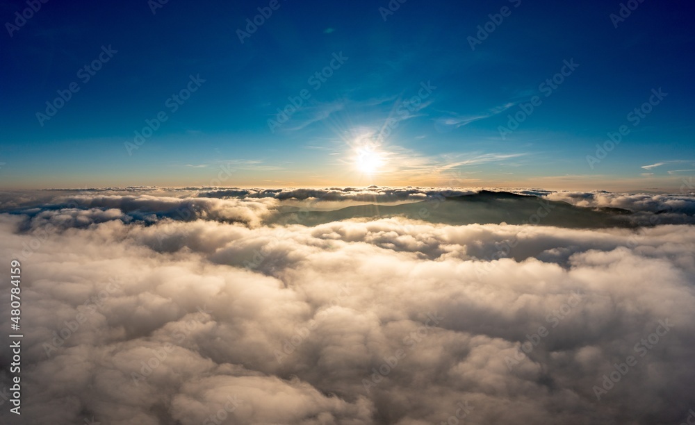 Sun shining brightly above white fluffy clouds at sunrise
