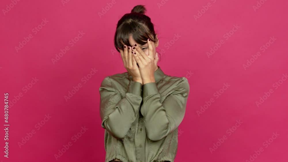 Pretty woman covering eyes by hands and looking through the fingers over isolated background Pretty woman covering eyes by hands and looking through the fingers over isolated background