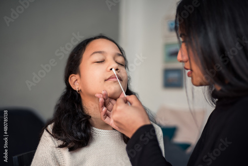 Mother introducing nasal swab test stick to detect possible Coronavirus infection at home. photo