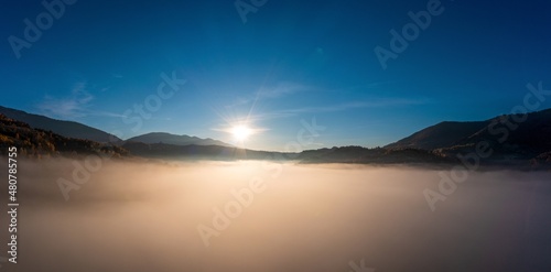 Sunset light among clouds above mountainous canyon in mist