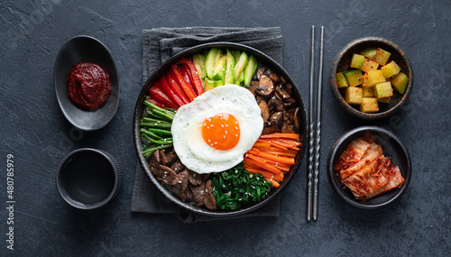 Fotografía Bibimbap on a dark concrete background, traditional korean dish, top view