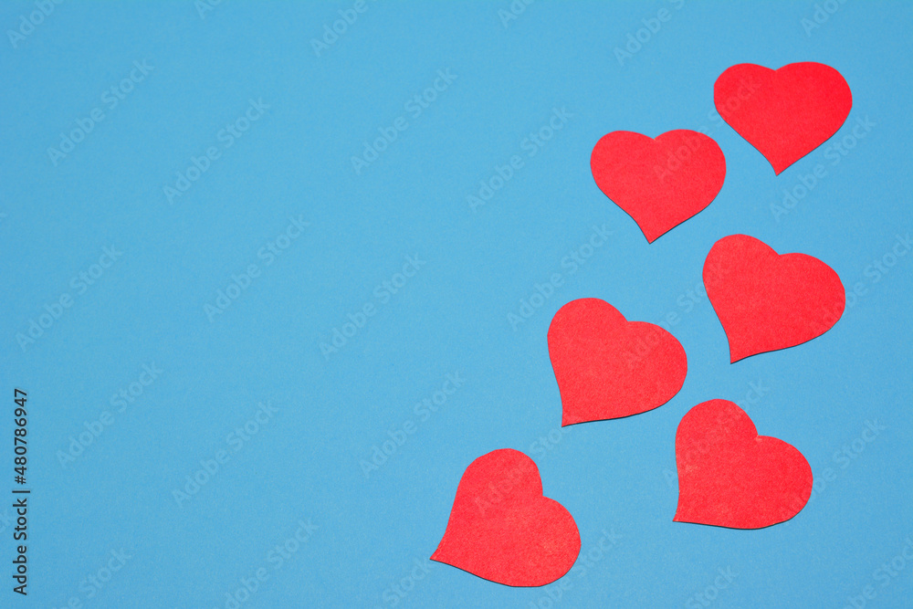 scarlet paper hearts on blue background, copy space