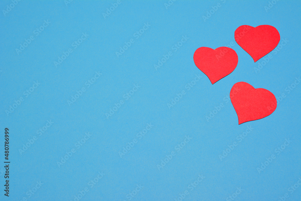 red paper hearts on blue background, place for text