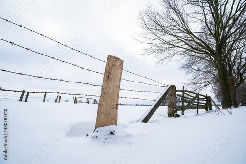 Verschneite Winterlandschaft - Stacheldraht und Holzpforte im Schnee. photo