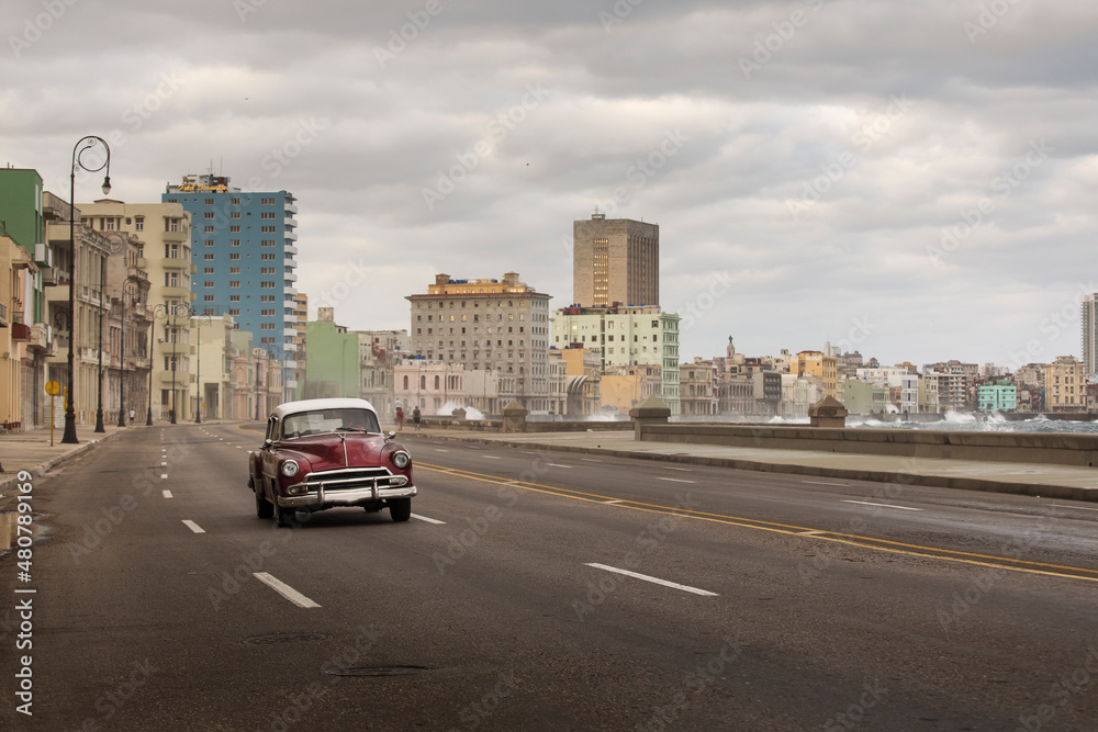 Old car on Malecon street of Havana with storm clouds in background. Cuba