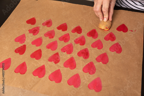 heart shaped potato stamp on craft paper. The process of decorating a gift for Valentine's Day. Getting ready for the celebration on February 14th.