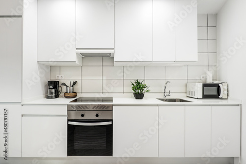 wall covered with white kitchen furniture with white silestone countertop and rectangular tiles