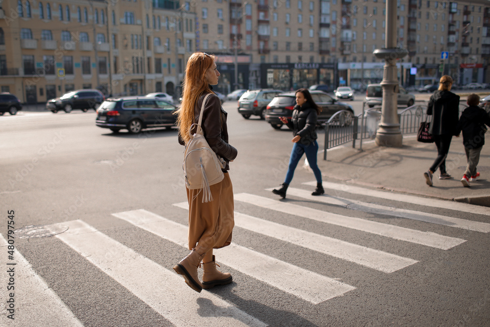 a woman crosses the road at a pedestrian crossing. woman in the city