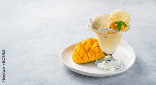 Mango ice cream and fresh mango on a gray background.